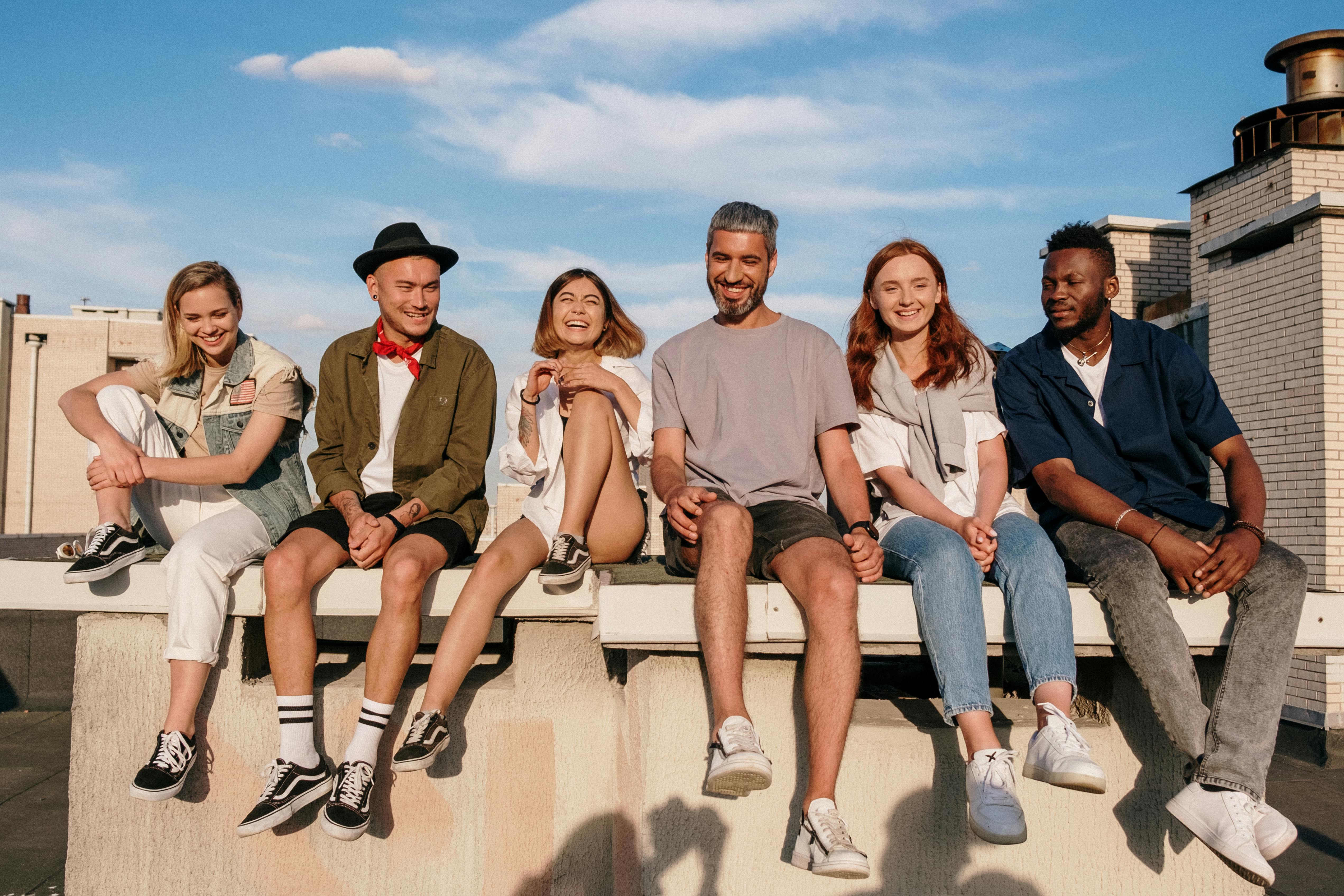 group of men and women sitting on a ledge on a sunny day