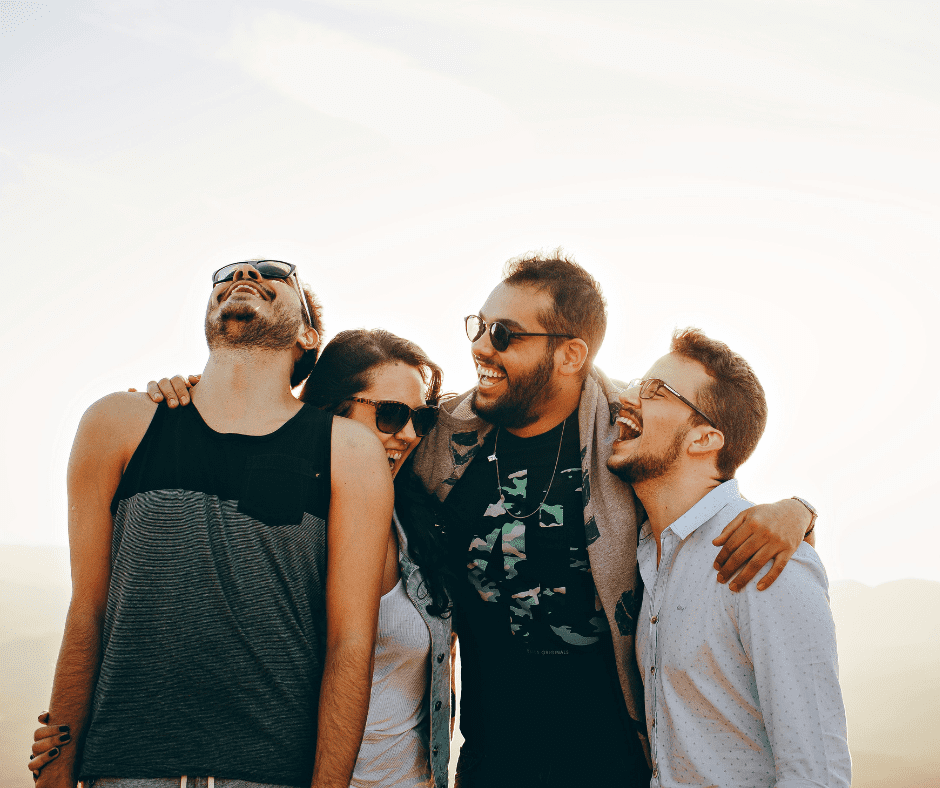 three men and a woman laughing with arms around shoulders