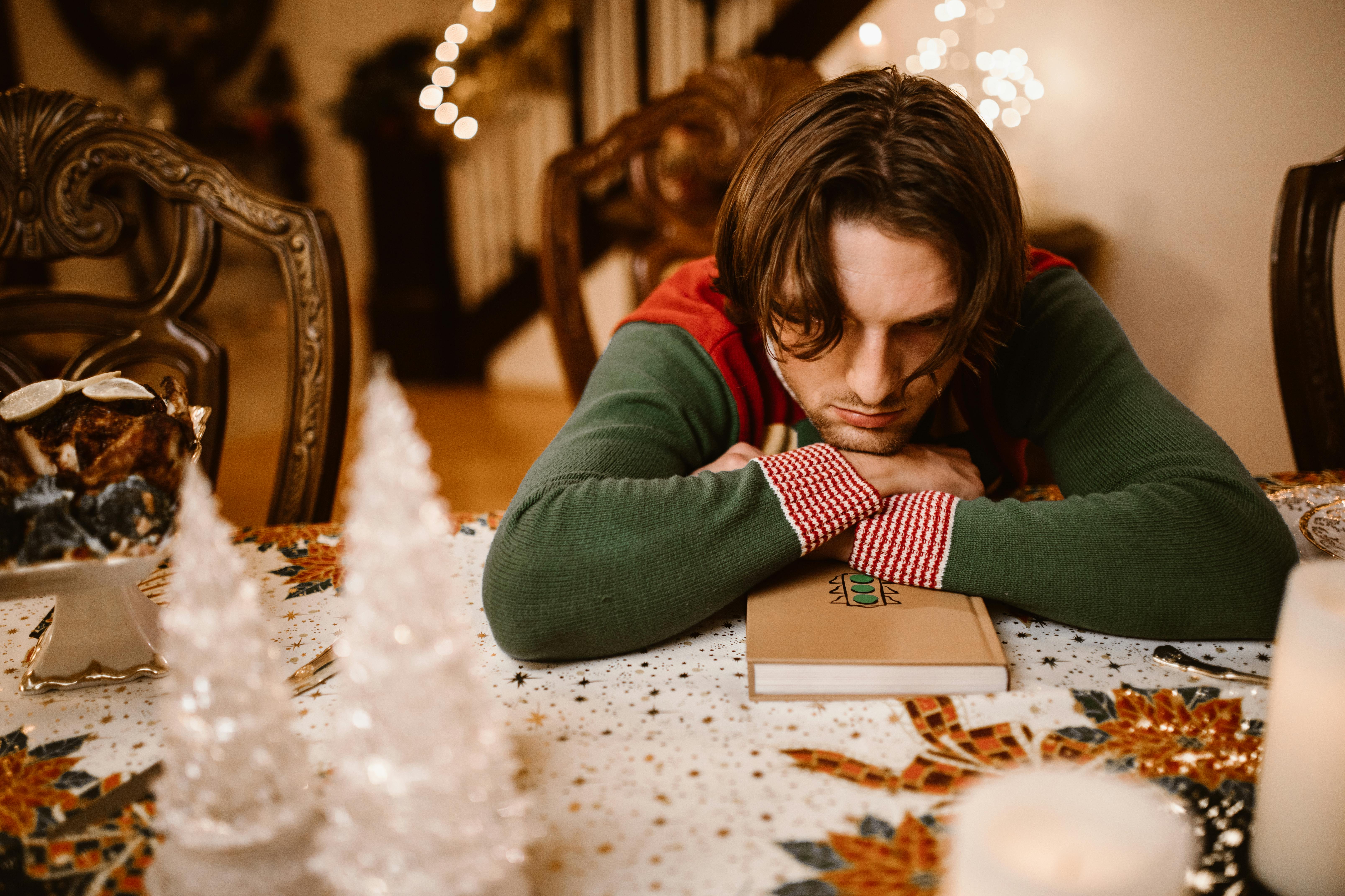 discouraged man in green and red Christmas sweater rest head on hands