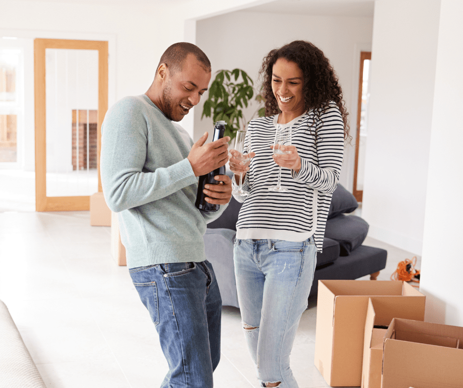 Smiling newlywed couple relaxing in their new home, toasting with glasses of wine to celebrate their fresh start