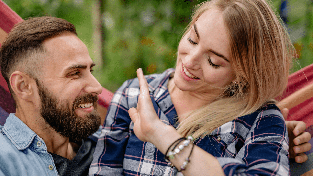 A smiling couple sitting together on a hammock