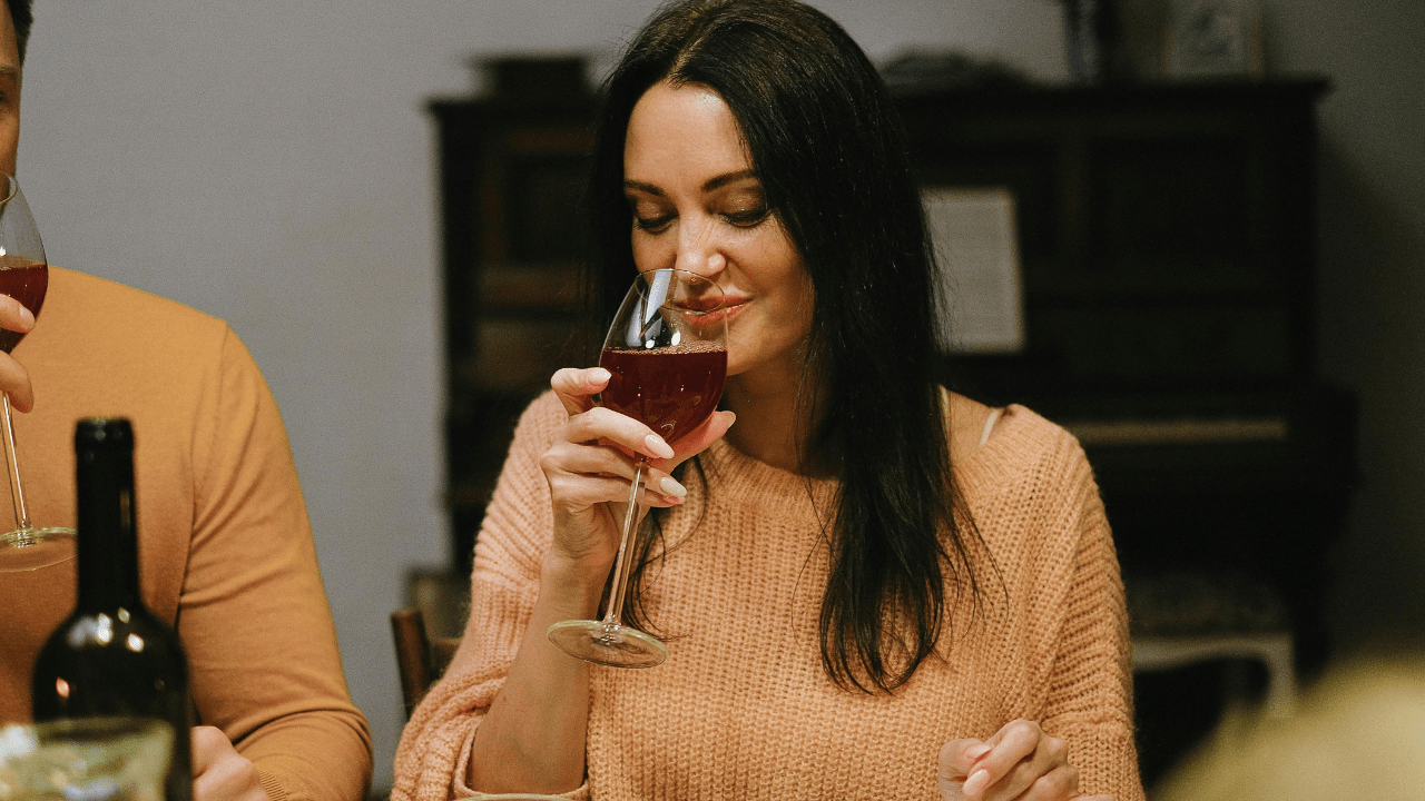 Woman in knitted sweater drinking wine