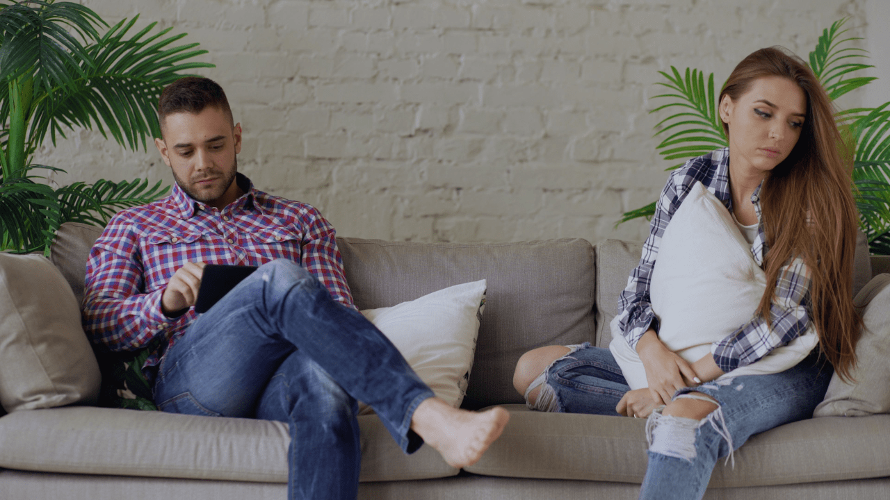 Man and woman sitting apart on a couch, illustrating relationship struggles and how couples therapy can help reconnect